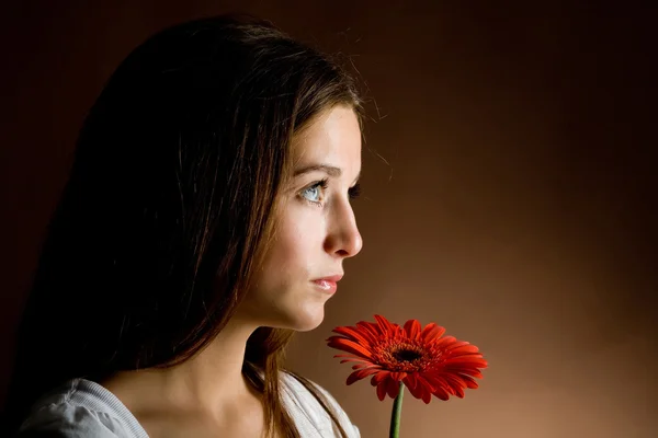 Νεαρή γυναίκα με ένα κόκκινο λουλούδι Εικόνα Αρχείου