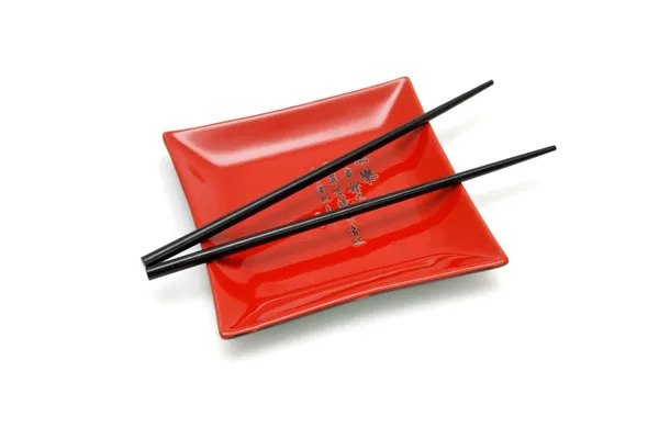 Black chopsticks on red square plate — Stock Photo, Image