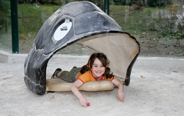 Cute little girl lies in turtle shell — Stock Photo, Image