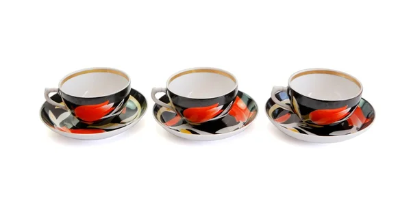 Row of three black tea cups with saucers — Stock Photo, Image