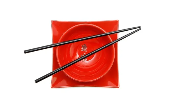 Bacchette nere su ciotola e piatto rosso — Foto Stock