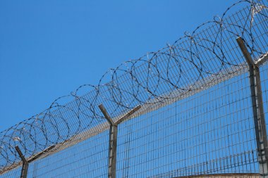 Fence with spiral barbed wire on top clipart