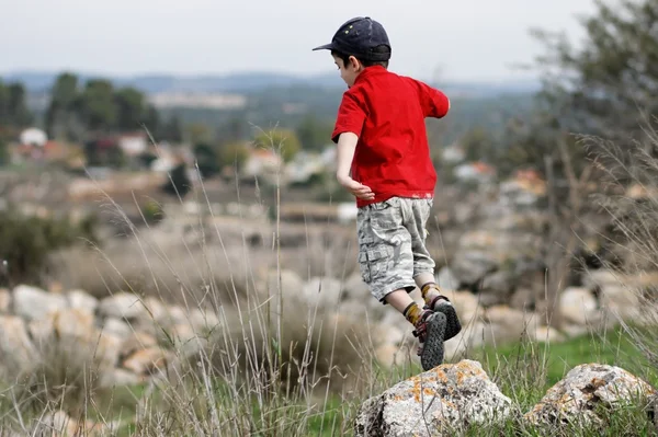 Liten pojke hoppar från stenen utomhus — Stockfoto