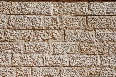 Wall built of beige stone blocks clipart