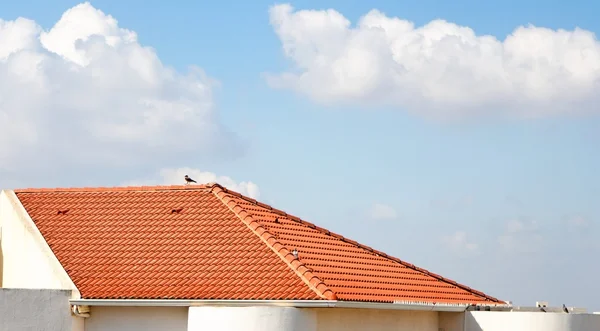 Turuncu kiremitli çatının bulutlu mavi gökyüzü altında — Stok fotoğraf