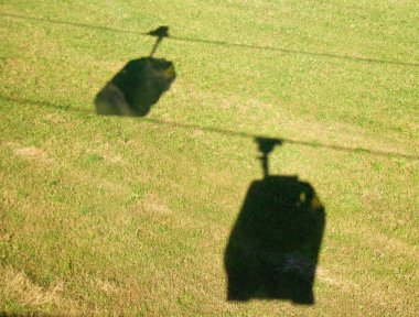 Shadows of cable cars on the grass clipart