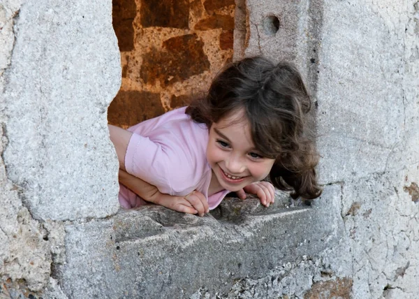 Smiling girl leans out of castle window — Stock Photo, Image