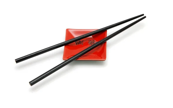 Chopsticks on small red square saucer — Stock Photo, Image
