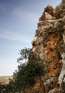 Steep weathered cliff face over dark sky clipart