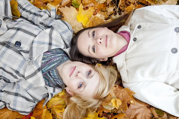 Δύο κορίτσια που βρίσκονται στα φύλλα — Φωτογραφία Αρχείου
