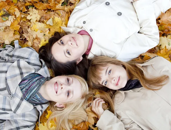 Три девушки лежат в листьях — стоковое фото