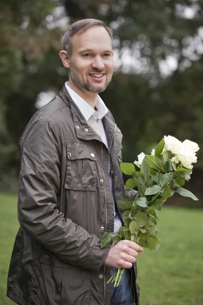 Muž s květy venku — Stock fotografie