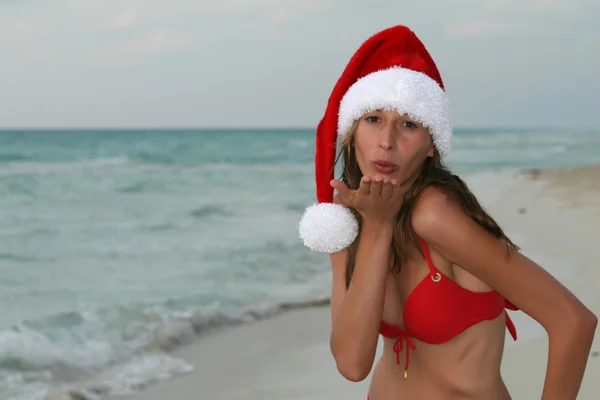 Kvinna hälsar på stranden i santa hatt — Stockfoto