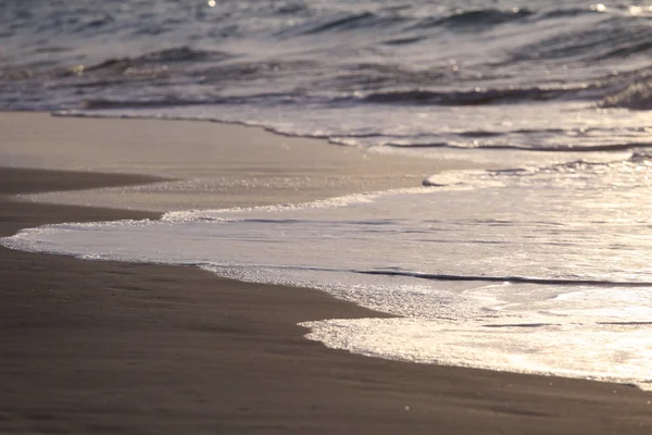 Волна и песок на закате — стоковое фото