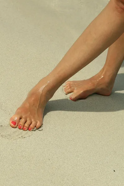 Weibliche Beine am Strand — Stockfoto