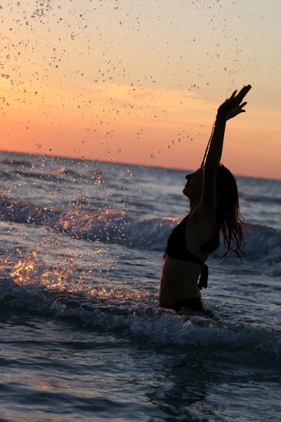 Woman splashing by sunset — Stock Photo, Image