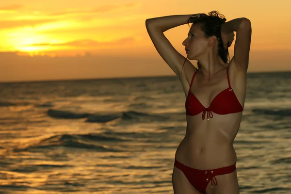 Kobieta na plaży przy zachodzie słońca — Zdjęcie stockowe