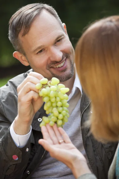 Man offers grapes to woman — Stock Photo, Image