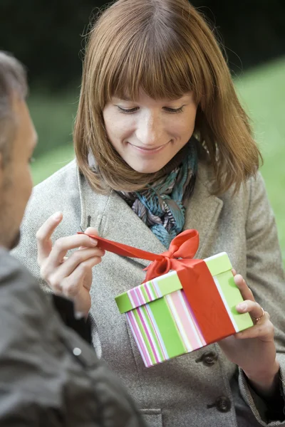 Woman opening gift box outdoors — Stock Photo, Image