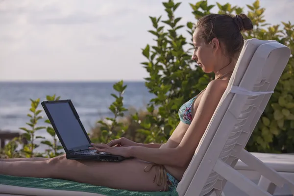 Kvinna i bikini med laptop — Stockfoto