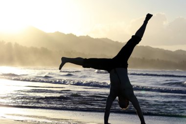 Man turns cartwheels on the beach clipart