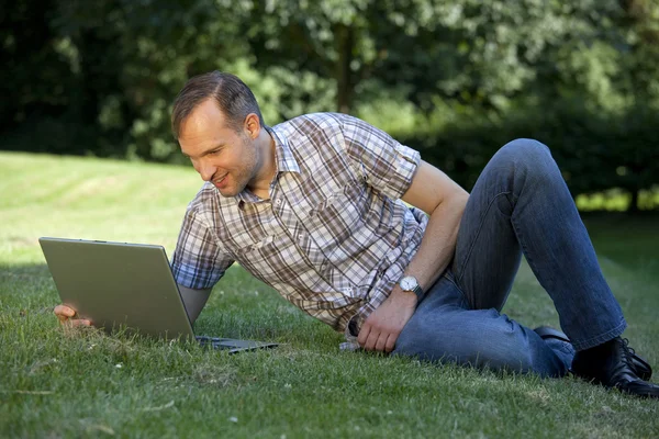 Homme avec ordinateur portable sur l'herbe — Photo