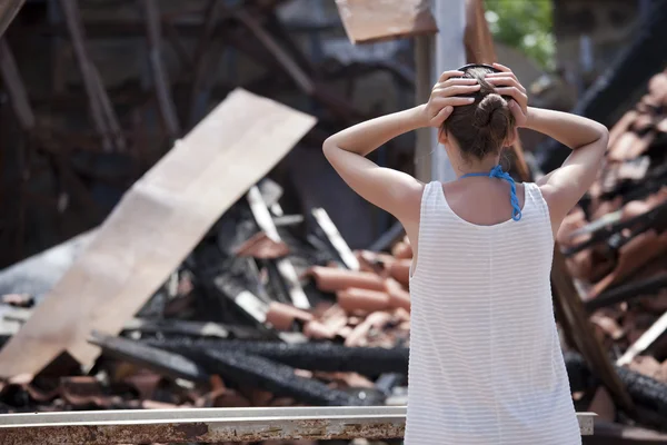 Женщина перед сгоревшим домом — стоковое фото