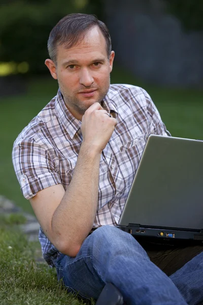 Pensando hombre con laptopn al aire libre — Foto de Stock