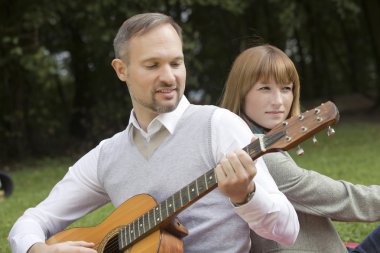 Adam akustik gitar çalıyor.