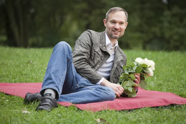 Man with flowers in park — Stock Photo, Image