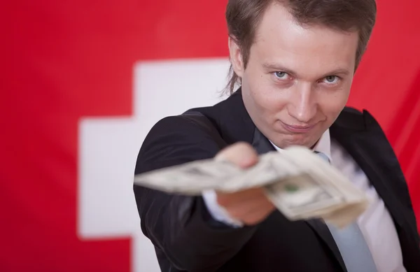 Άνθρωπος με χρήματα πάνω από τη σημαία της Ελβετίας — Φωτογραφία Αρχείου