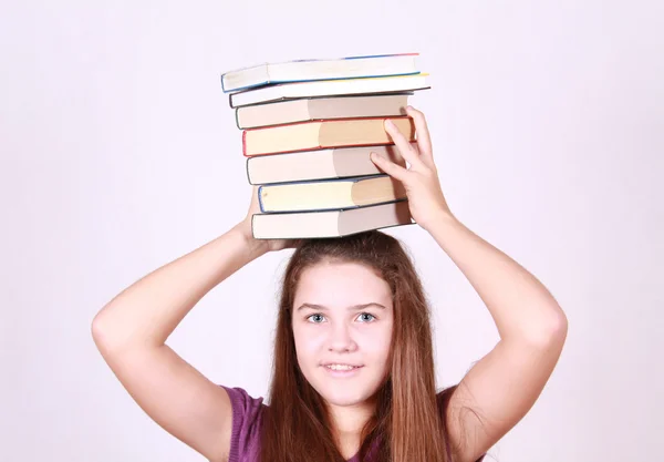 Schoolgirl keeps much books on head — Stock Photo, Image