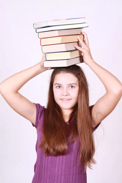 Teenager keeps much books on head — Stock Photo, Image