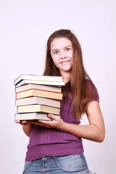 Schoolgirl keeps in hand pile books — Stock Photo, Image