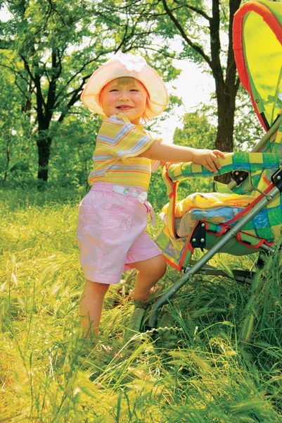 Chica en el bosque cerca de carro de bebé — Foto de Stock