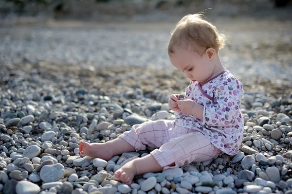 Маленький ребенок, сидящий на камнях у — стоковое фото