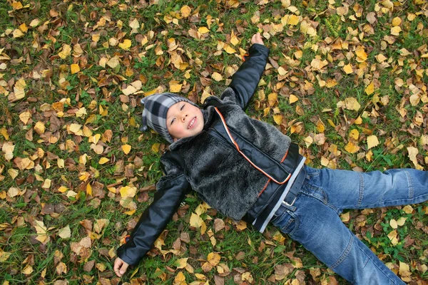 The boy lays on the ground covered by au — Stock Photo, Image