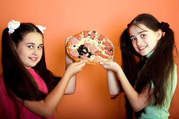 Two young girls show on pizza — Stock Photo, Image