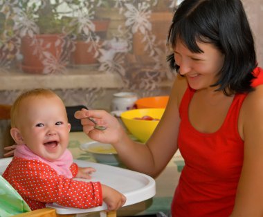 Mother feeds the little daughter clipart