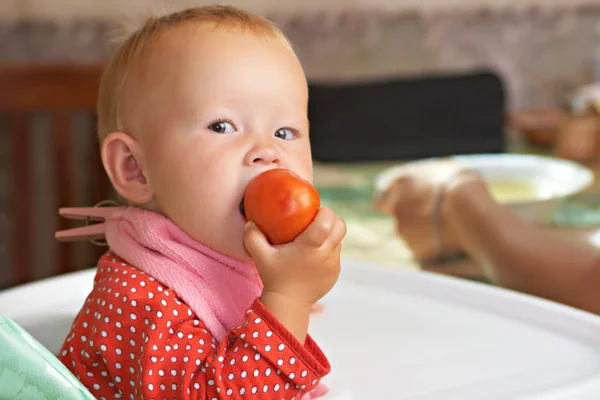 O miúdo come um tomate. — Fotografia de Stock