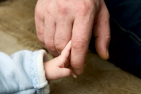 Pequena criança que guarda o dedo de pai — Fotografia de Stock