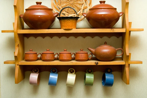 Ceramic utensils on a wooden shelf — Stock Photo, Image