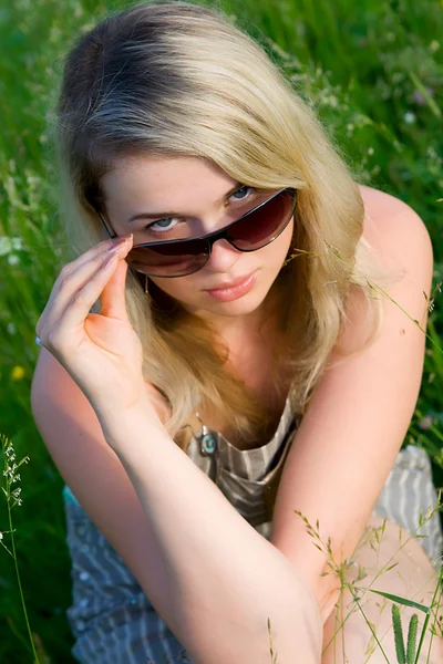 The young girl in sunglasses on grass — Stock Photo, Image