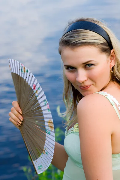 stock image The young girl with a fan in hands