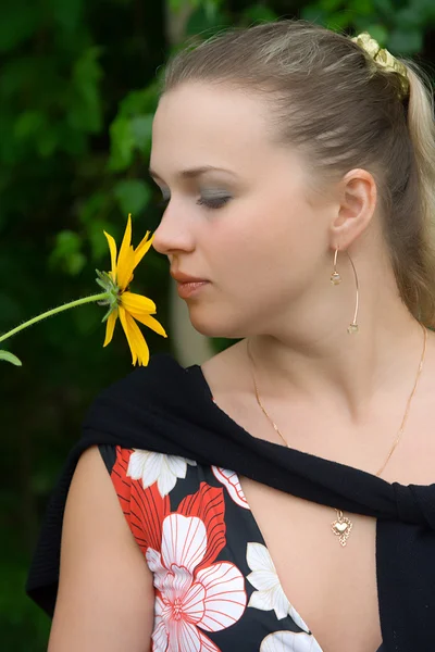 Het jonge meisje met een gele bloem — Stockfoto