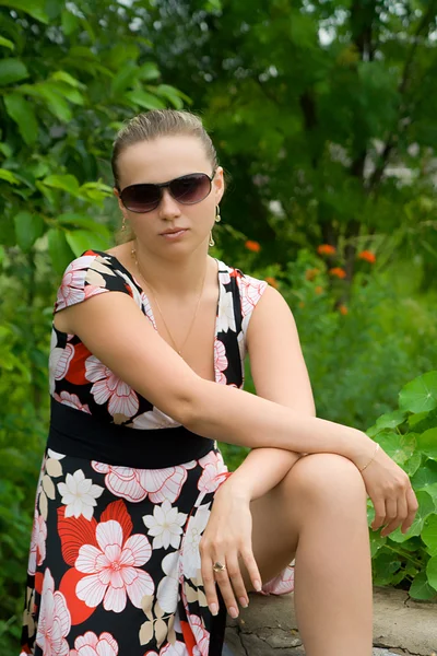 Bir çim üzerinde güneş gözlüklü genç kız — Stok fotoğraf