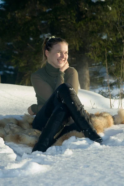 Ung flicka sitter på snö i trä. — Stockfoto