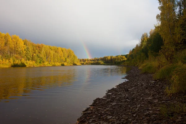 Rainbow over river in clouds — Stock Photo, Image