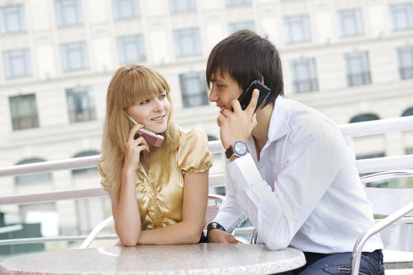 Couple sitting at table using their cell — Stock Photo, Image