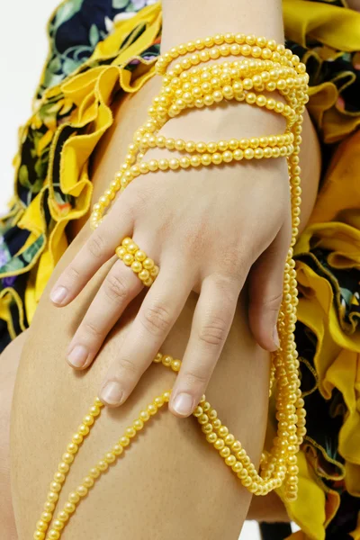 stock image Hand holding string of yellow pearls.